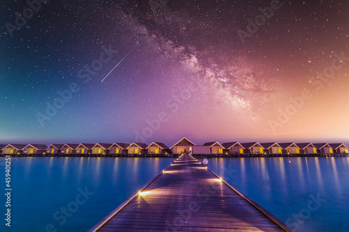 Luxury over water villas, bungalows sea ocean with beach at night sunset time, Milky Way. Exotic adventure carefree travel vacation, summer resort landscape. Fantasy nature resort hotel landscape