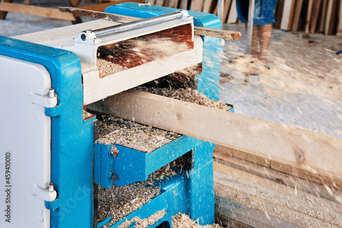 A wood plate passing through the thickness planer machine in a carpentry workshop.