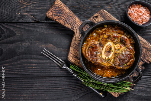 Stew veal shank meat OssoBuco, italian osso buco steak. Black wooden background. Top view. Copy space