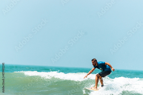 Mężczyzna surfer płynący na fali na tle błękitnego oceanu i nieba.