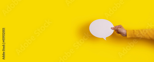 Talk bubble speech icon in hand over yellow background, panoramic layout