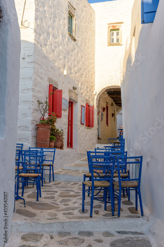 Traditional cycladitic alley with a whitewashed facades and an exterior of a cafe in chora Amorgos Greece