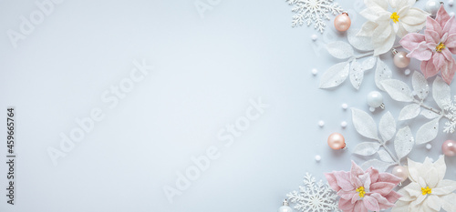 Christmas arrangement with festive baubles, poinsettia flowers and silver leaves on pastel background. Flat lay. Top view, copy space.