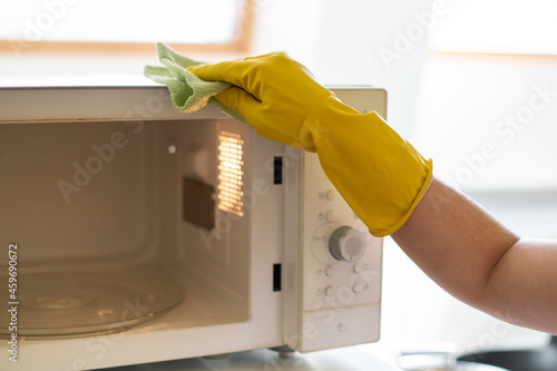 Professional cleaning of apartments and houses. General cleaning in the kitchen. Wipe the plate and surfaces. Washing the faucet and sink. Cleaning lady in uniform, apron, rubber gloves