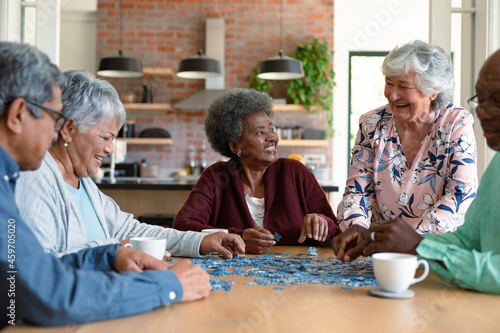 Group of diverse senior male and female friends doing puzzles at home