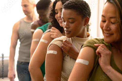 Group of diverse female and male friends showing plasters after vaccination