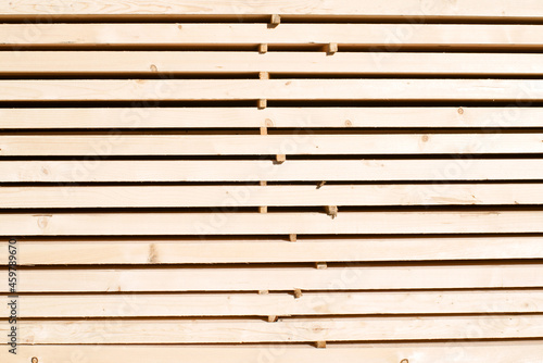 Background from wooden boards close-up. Stacked stacks of wooden planks. Lumber warehouse, wood drying, building material.