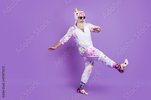 Full length body size view of nice funny cheerful man in pajama walking having fun isolated over violet purple color background