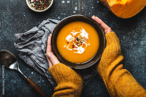 Female hands with bowl of pumpkin soup