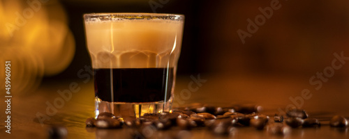 shot with coffee in the glass and coffee beans on wooden table in bar panorama
