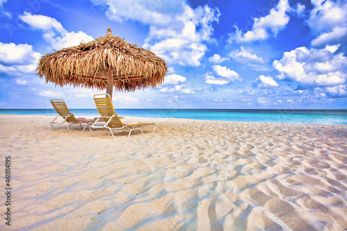 Thatch umbrella and deckchairs on an ideally sandy coast