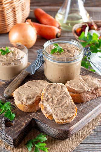 Fresh homemade chicken liver pate on bread on rustic background