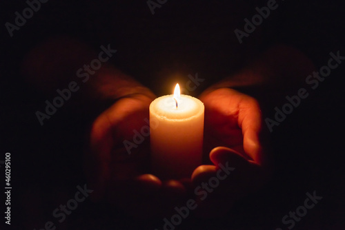 Hands holding burning candle in dark like a heart.Selective focus,black background.