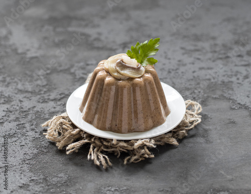 Pudding of champignons with parsley greens on a plate on a linen napkin on a dark gray background in rustic style in rustic style
