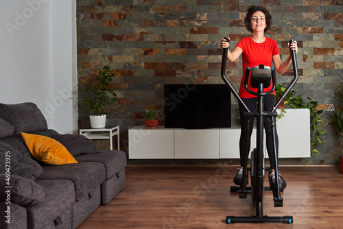Woman training at home using elliptical cross trainer