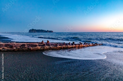 sunset in the beach with huge tree trunks from the coastal forest scattered in Rialto beach in Olympic national park in Washington State