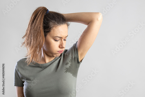 Young woman with her arm raised with her armpits sweat