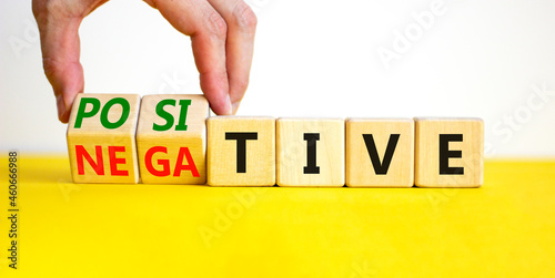 Positive or negative symbol. Businessman turns wooden cubes and changes the word 'negative' to 'positive'. Beautiful yellow table, white background. Business, positive or negative concept. Copy space.