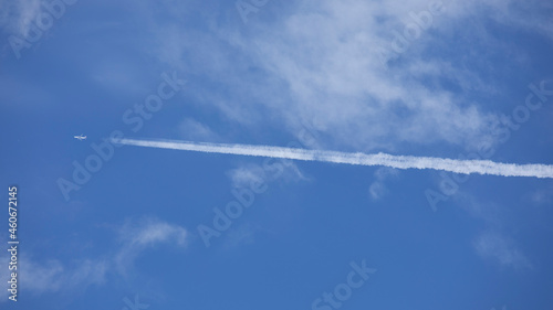 Avion de tourisme traçant une ligne blanche sur le ciel bleu et nuageux au moment des vacances d'été.