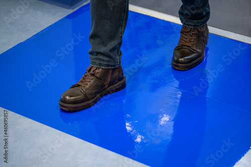 Man in brown shoes stepping on blue Adhesive Sticky Mats.