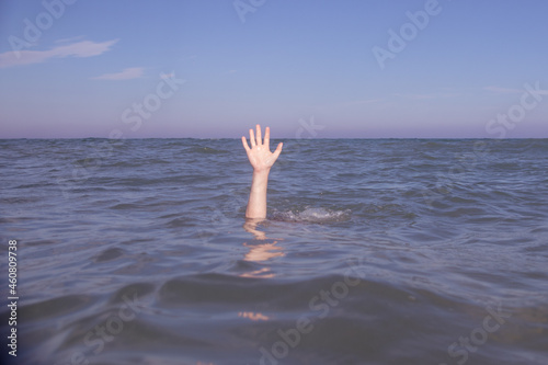 Person submerged on a beach with hand out pretending to be drowning