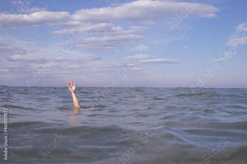 Person submerged on a beach with hand out pretending to be drowning