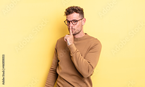 young handsome hispanic man asking for silence and quiet, gesturing with finger in front of mouth, saying shh or keeping a secret