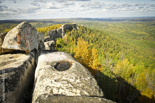 Indian summer in the mountains, rocks with swollen edges and stone bowl, autumn. Granite rock massif of the Middle Urals - Mount Arakulskie Shikhany, Chelyabinsk region, Russia.