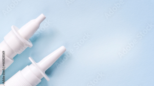 2 white nasal sprays on a light blue background. The concept of autumn diseases, allergies.