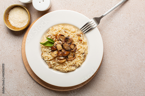 A plate of risotto with mix of mushroom and taleggio cheese on stone beige table. Top view. Copy space