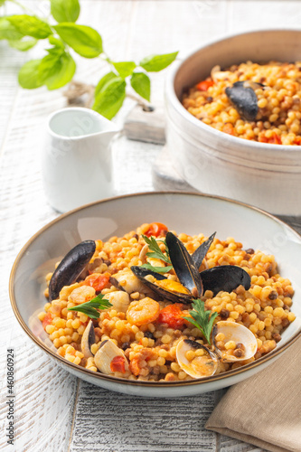 Seafood pasta. Sardinian Fregula with seafood on a white wood surface.