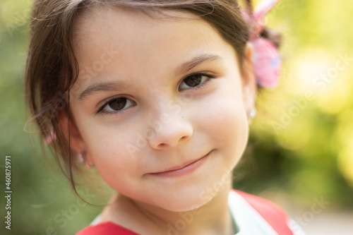 Close-up portrait of little smiling cute white girl on blurred background