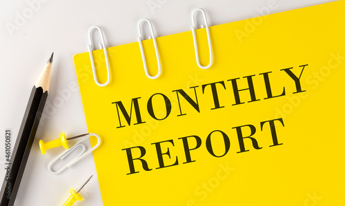 MONTHLY REPORT word on the yellow paper with office tools on white background