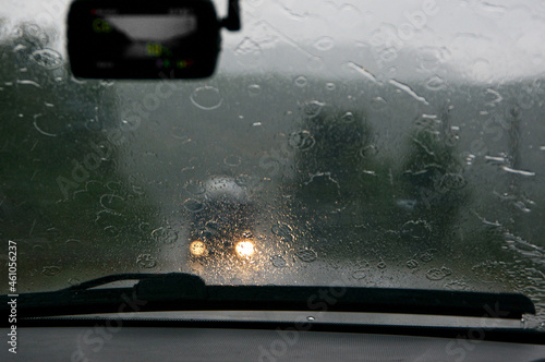 View on road and oncoming traffic in rain through windscreen of moving car