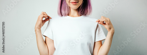 Pretty plus size model with white blank t-shirt and pink hear, empty grunge wall background. Holding her shirt and smiling, no face