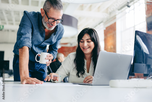 Two happy colleagues collaborating on a new project in the offic