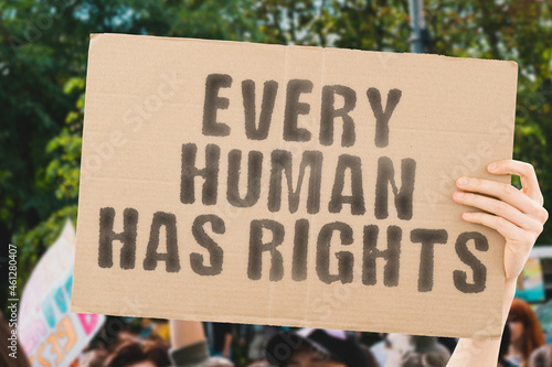 The phrase " Every human has rights " on a banner in men's hand with blurred background. Protest. Street. Equality. Law. Rules. Freedom