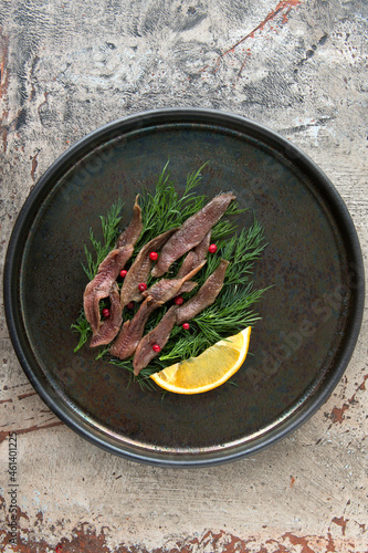flat lay plate of anchovy fillet with dill and lemon on the table