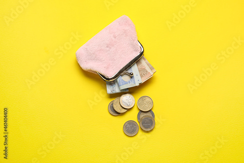 Pink wallet with money on yellow background