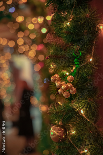 festive Christmas decoration with hanging toy balls and background blurry garland lights, vertical picture, focus on toy