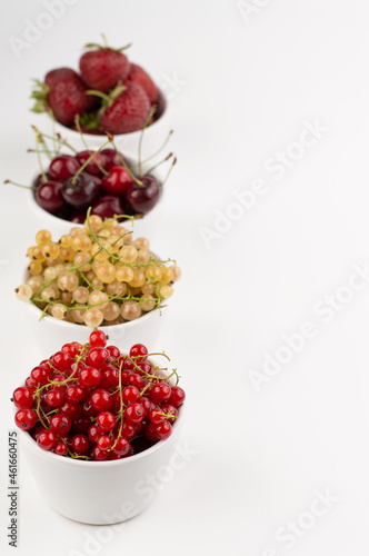 Blurred image of various fruits and berries in white plates on a white background with space for entering text.