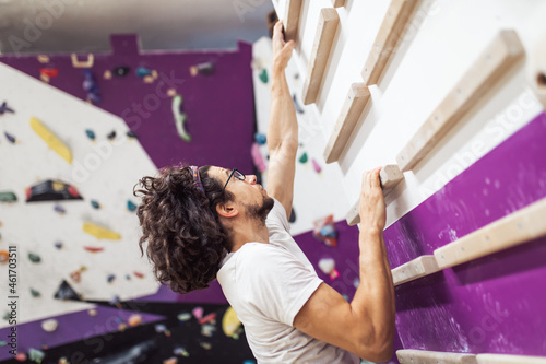 Sportsman climber climbing on artificial wall indoors. Extreme sports concept.