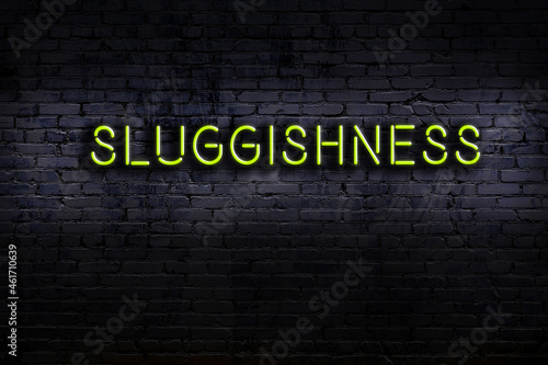 Night view of neon sign on brick wall with inscription sluggishness