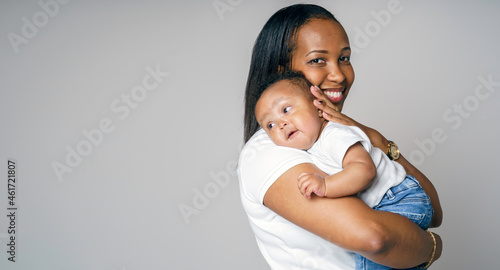 portrait of beautiful african woman holding on hands her little son on grey background