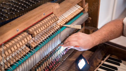 Of professional worker repairing and tuning an old English bayonet piano