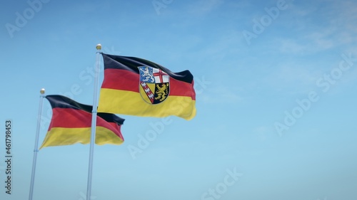 Waving flags of Germany and the German state of Saarland against blue sky backdrop. 3d rendering