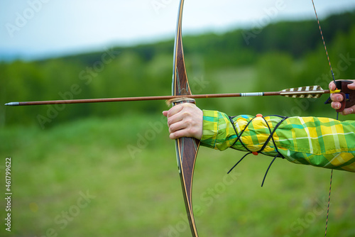 professional archer shooting with modern longbow in forest