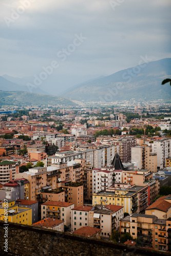 Aerial view of the mountains and the modern centre of Brescia (Lombardy, Italy) with tiled red roofs, chimneys, cathedral's domes and tall white brick old towers. Traditional European architecture.