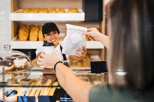 Beautiful young woman buying delicious baked goods in bakery. Rear view.