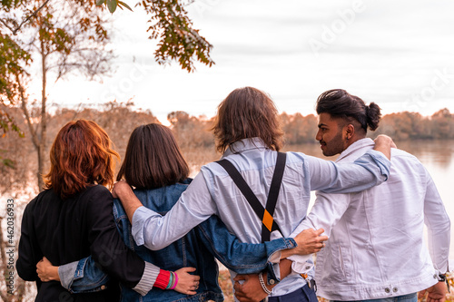 group of best friend have fun in front of a big river in autumn at sunset